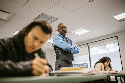 A professor supervises students during an exam, ensuring integrity in a classroom setting.