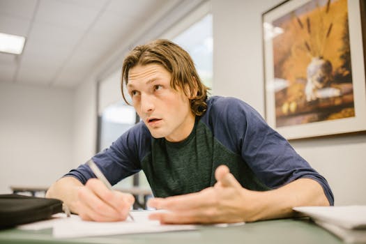 A college student intently focusing on a test in a classroom environment.