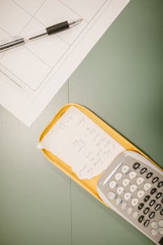 Closeup of a calculator with a hidden cheat sheet during an exam on a green desk.
