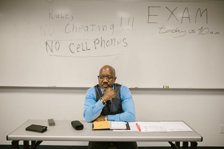 Teacher Sitting By His Desk