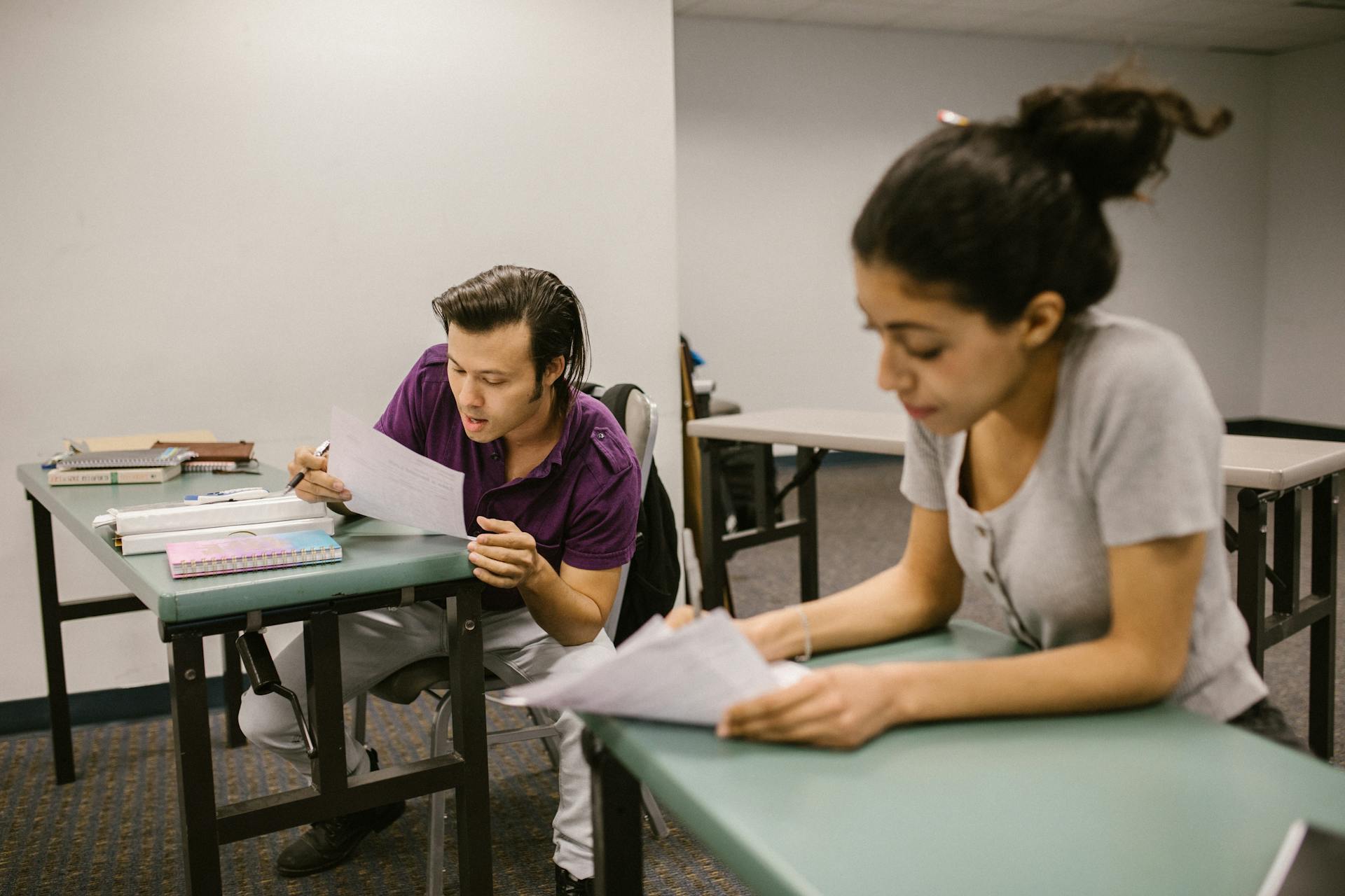 Two students collaborate in a college classroom during a study session.