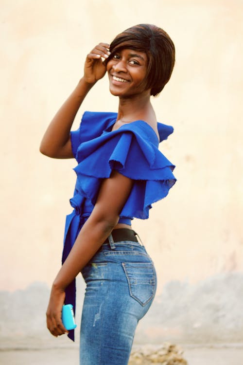 A Woman in Blue Top Smiling with Her Hand on Her Hair