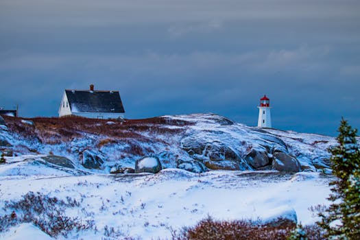 A picturesque winter scene featuring a lighthouse and snowy landscape under a dramatic sky.