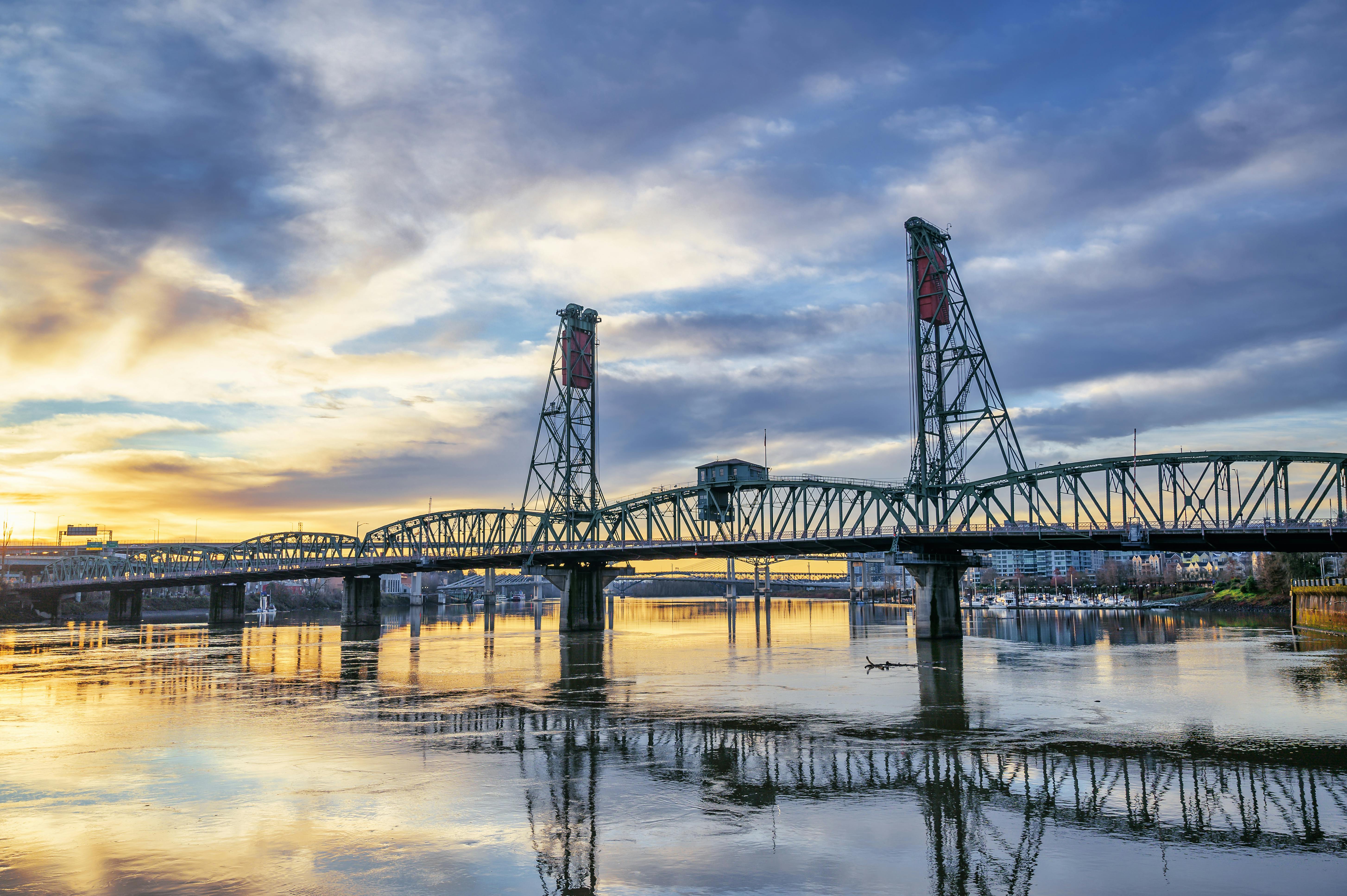 truss bridge over river under sundown sky