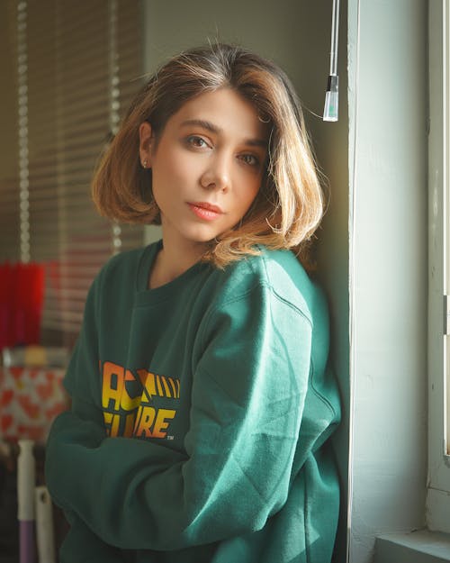 A Woman in Green Sweater Leaning on the Wall