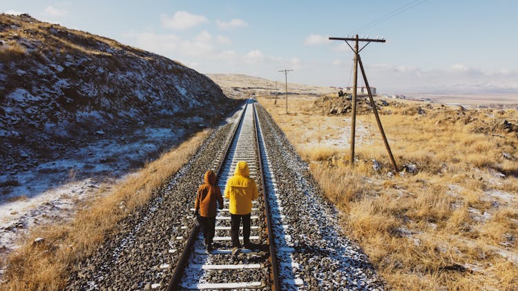 Two People Walking On The Railroad