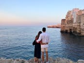 日落时分，在意大利滨海波利尼亚诺，一对夫妇在海边相拥