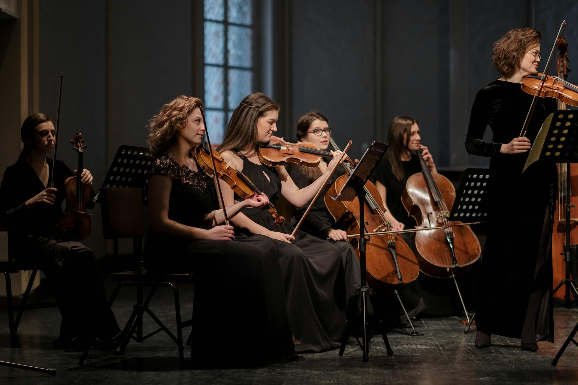 A group of female musicians playing classical music in a concert setting indoors.