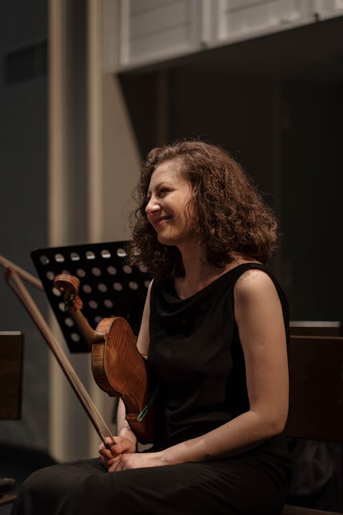 A Woman in Black Dress Playing Violin