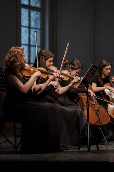 A group of women playing violins and cellos in a classical music performance indoors.