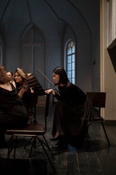 Women musicians in black dresses rehearsing in a church with music stands and instruments.