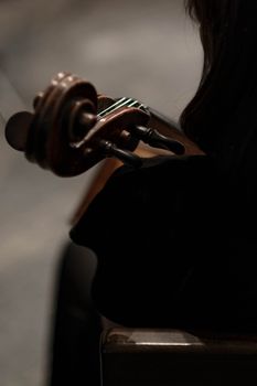 Close-up view of a violinist playing a string instrument in a dark setting, capturing the essence of music.