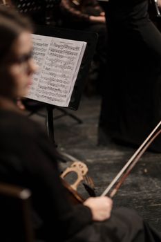 Blurred violinist with sheet music on stage, capturing a concert ambiance.