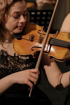 A woman in a black dress playing violin, focusing on classical music performance.