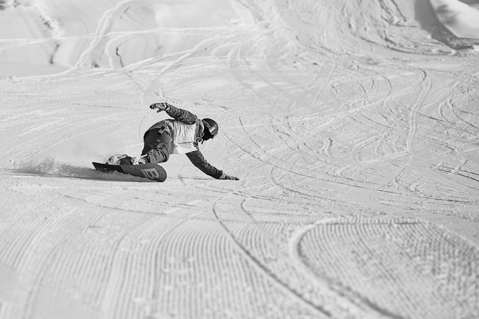 Anonieme snowboarder die op een besneeuwde helling naar beneden glijdt met helm en beschermende uitrusting