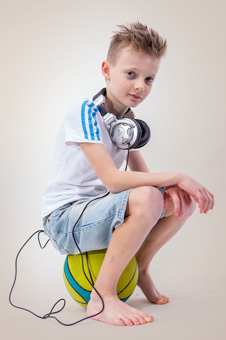 A Young Boy Sitting On The Ball