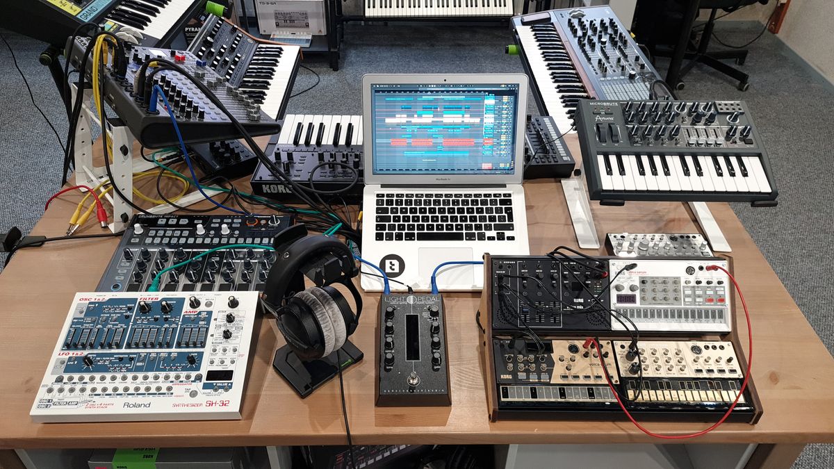 Modern electronic music production studio with synthesizers and laptop