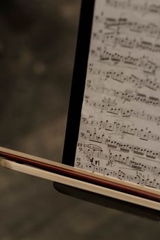 Detailed shot of sheet music with a bow, highlighting musical notes in focus.