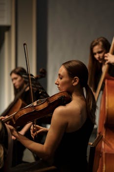 A focused woman plays the violin eloquently during a classical music concert.