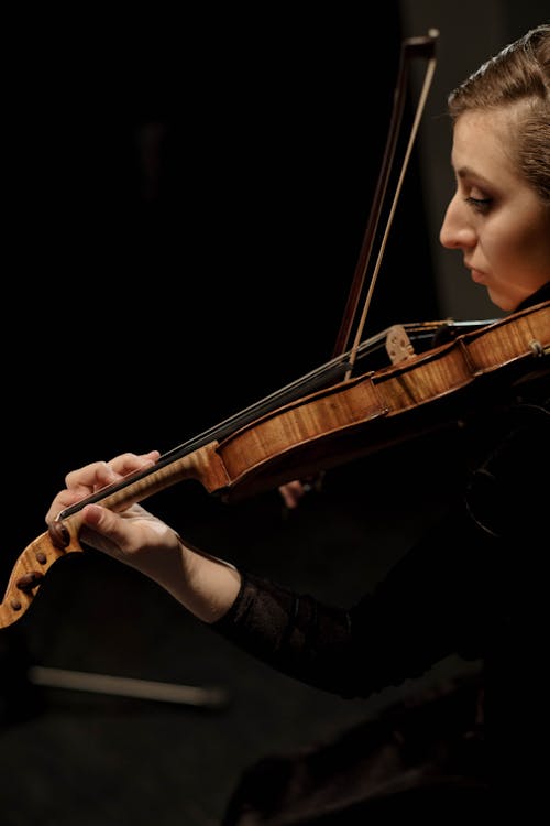 A Woman in Black Long Sleeves Playing a Violin