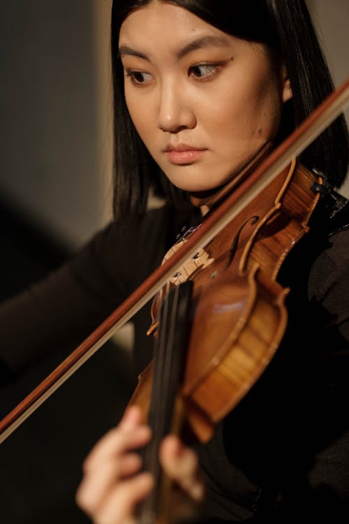A Woman in Black Long Sleeves Playing Violin