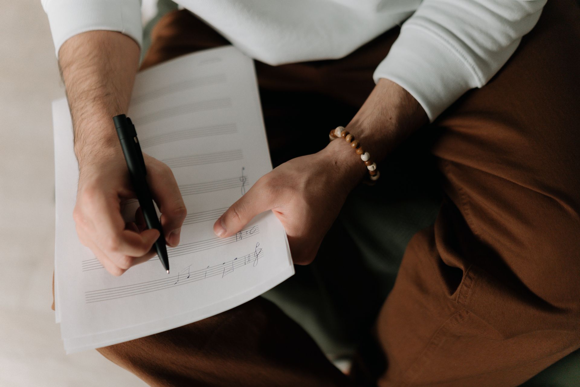 A songwriter composing lyrics and musical notes on sheet music