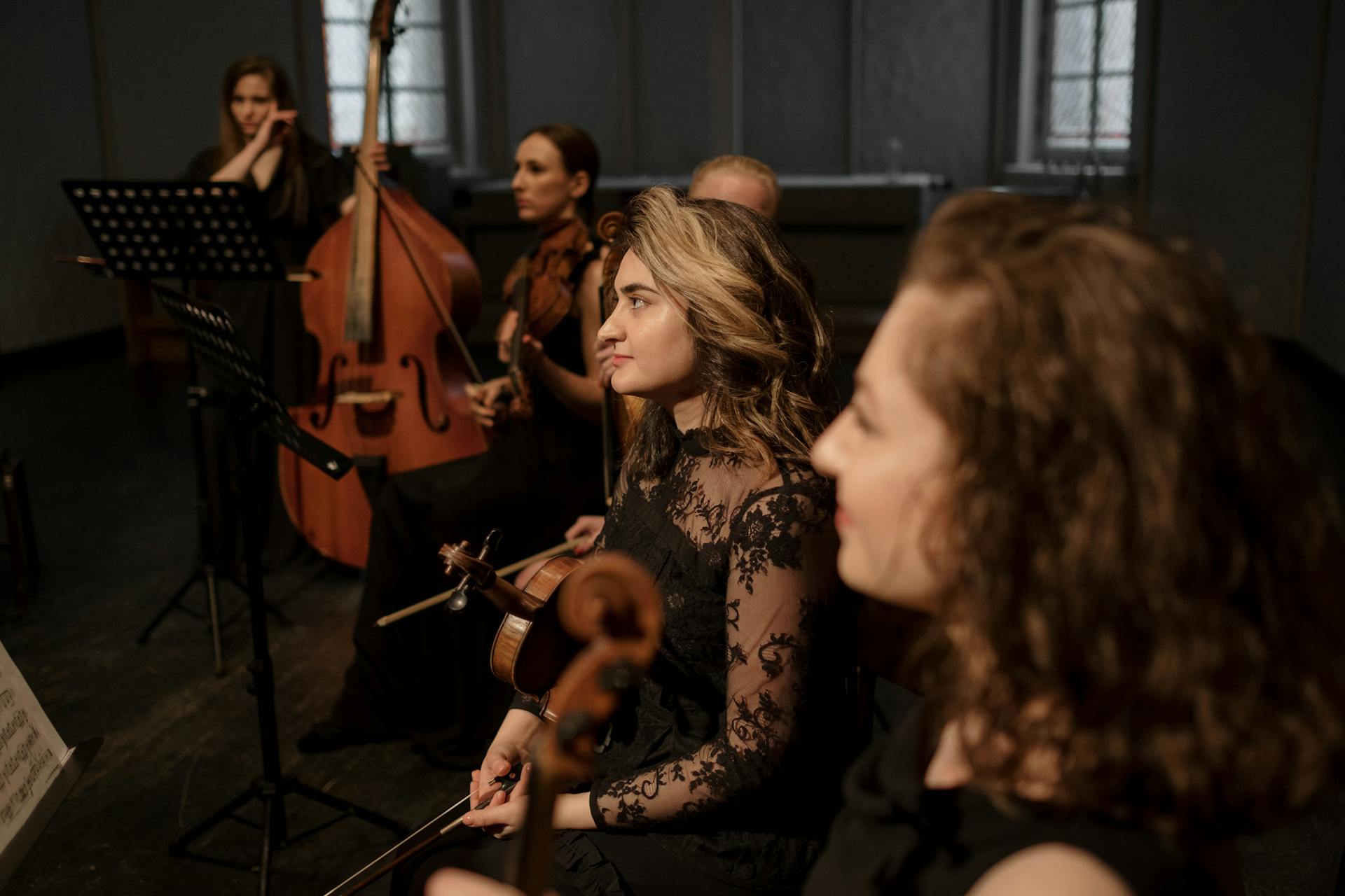 Group of orchestra musicians rehearsing with various instruments indoors.