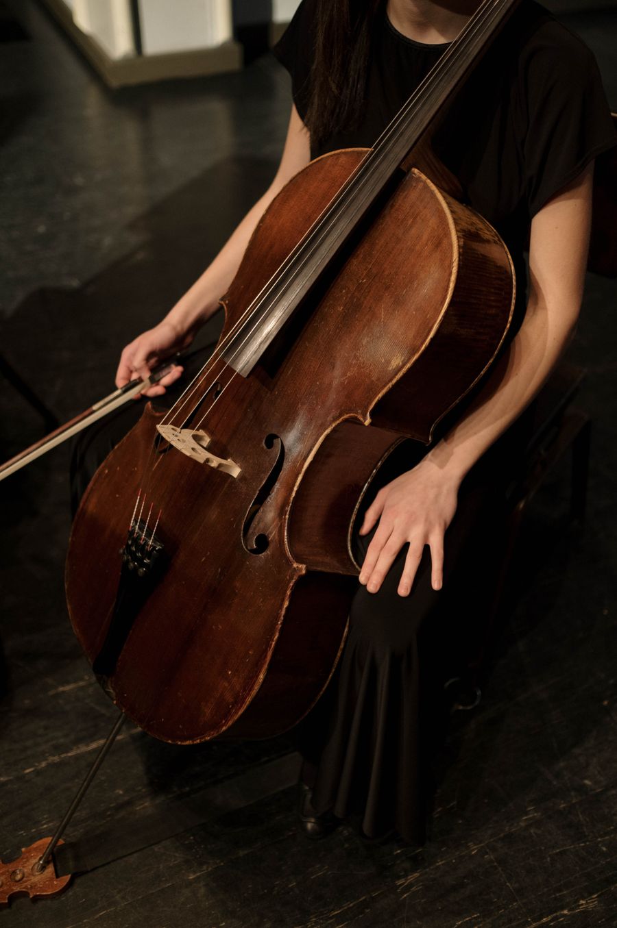 Violoncelista tocando com arco em ambiente escuro