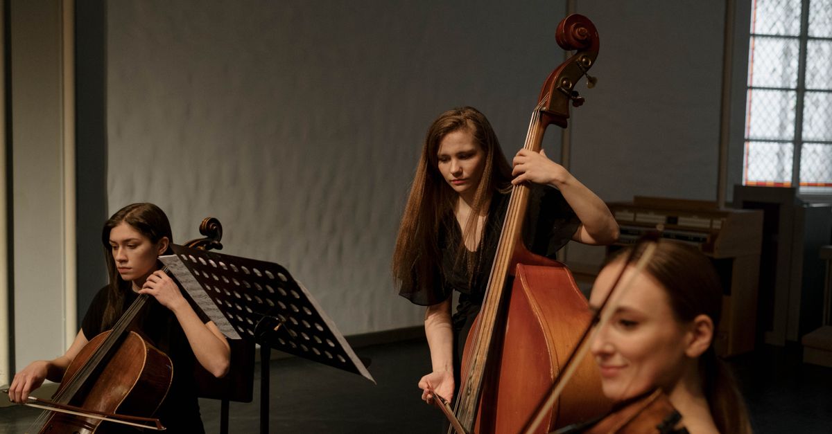 A trio of female musicians playing string instruments in a chamber music setting.