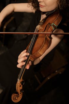 Close-up of a woman playing a violin, showcasing musical skill and elegance.