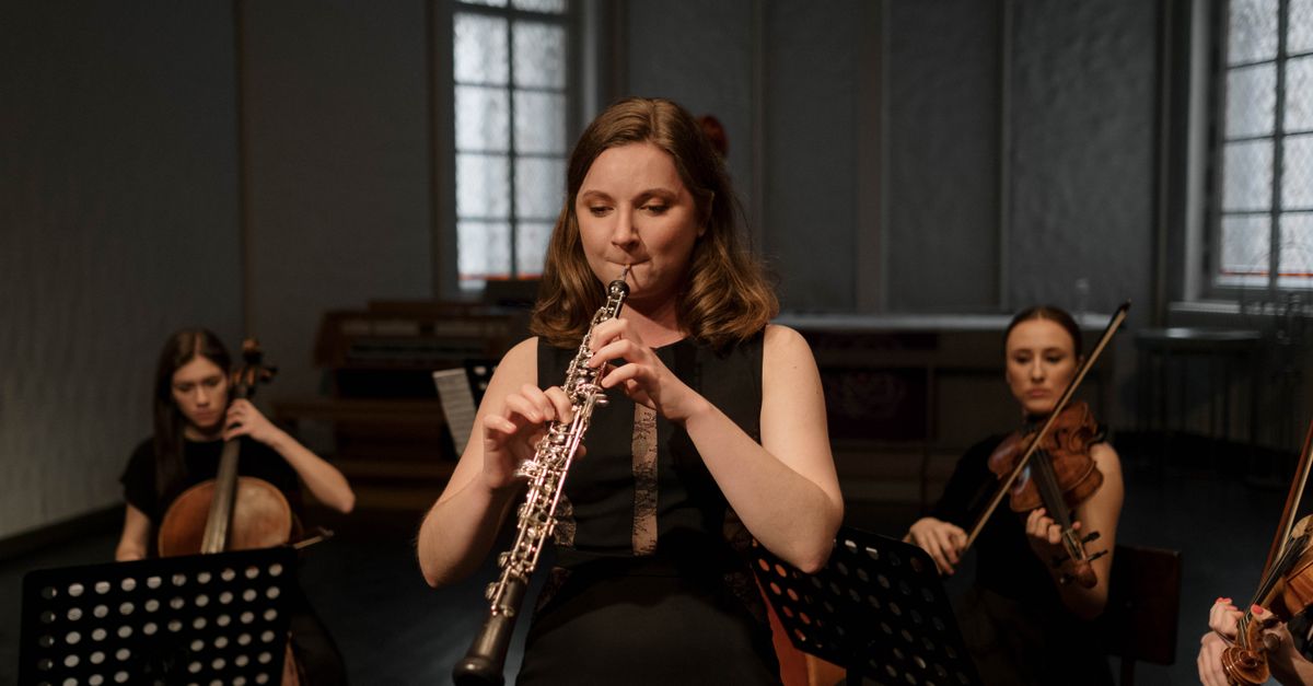 A woman playing the oboe during a classical music concert indoors.