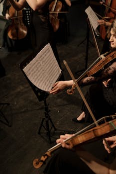 A high-angle view of orchestra musicians performing with sheet music on stage.