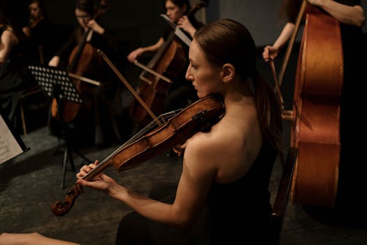 Female violinist playing in an orchestra during an indoor concert.