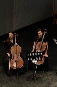 Cellists sitting with cellos on stage during a concert performance.
