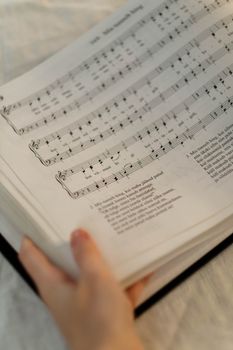 Close-up view of a hand holding open sheet music with musical notation.