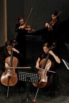 Women musicians playing violins and cellos during an indoor concert performance.