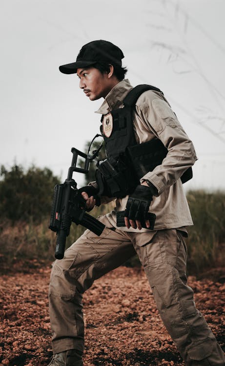 A Man Wearing a Military Uniform Holding a Firearm · Free Stock Photo