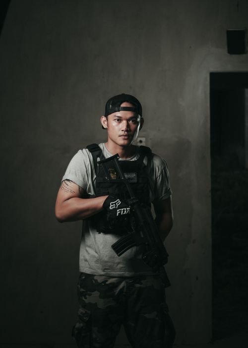 Free A serious man indoors wearing a bulletproof vest and holding a rifle. Stock Photo