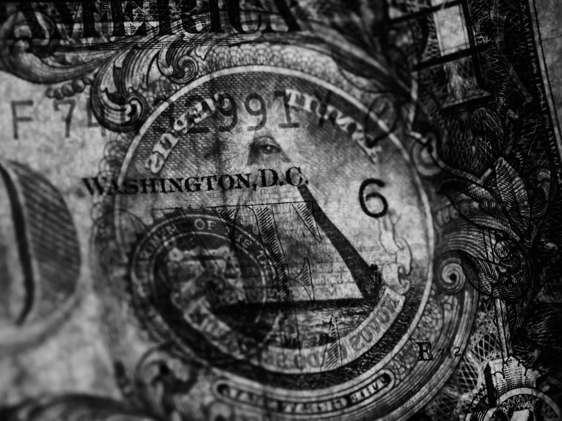 Detailed close-up of a US dollar bill in grayscale highlighting symbols and textures.