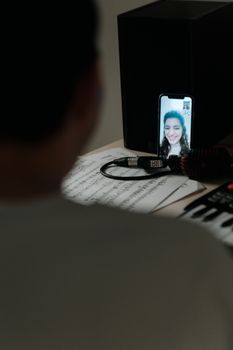 Musician having a virtual lesson with sheet music and a smartphone video call.