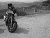 一张黑白图像中，一辆摩托车停在葡萄牙布拉干萨乡村风景优美的道路上