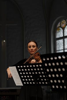 Female violinist performing in a classical indoor setting with music sheets.