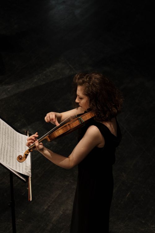Free A woman violinist performs with music sheet visible, captured from above. Stock Photo