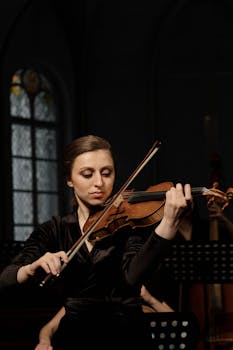 A female violinist performs passionately during a classical concert indoors.