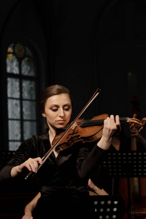 Free A female violinist performs passionately during a classical concert indoors. Stock Photo
