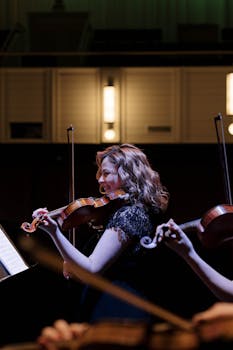 Woman violinist playing passionately on stage during a symphony concert.