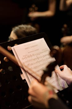 Close-up of a musician reading sheet music during an orchestra performance.