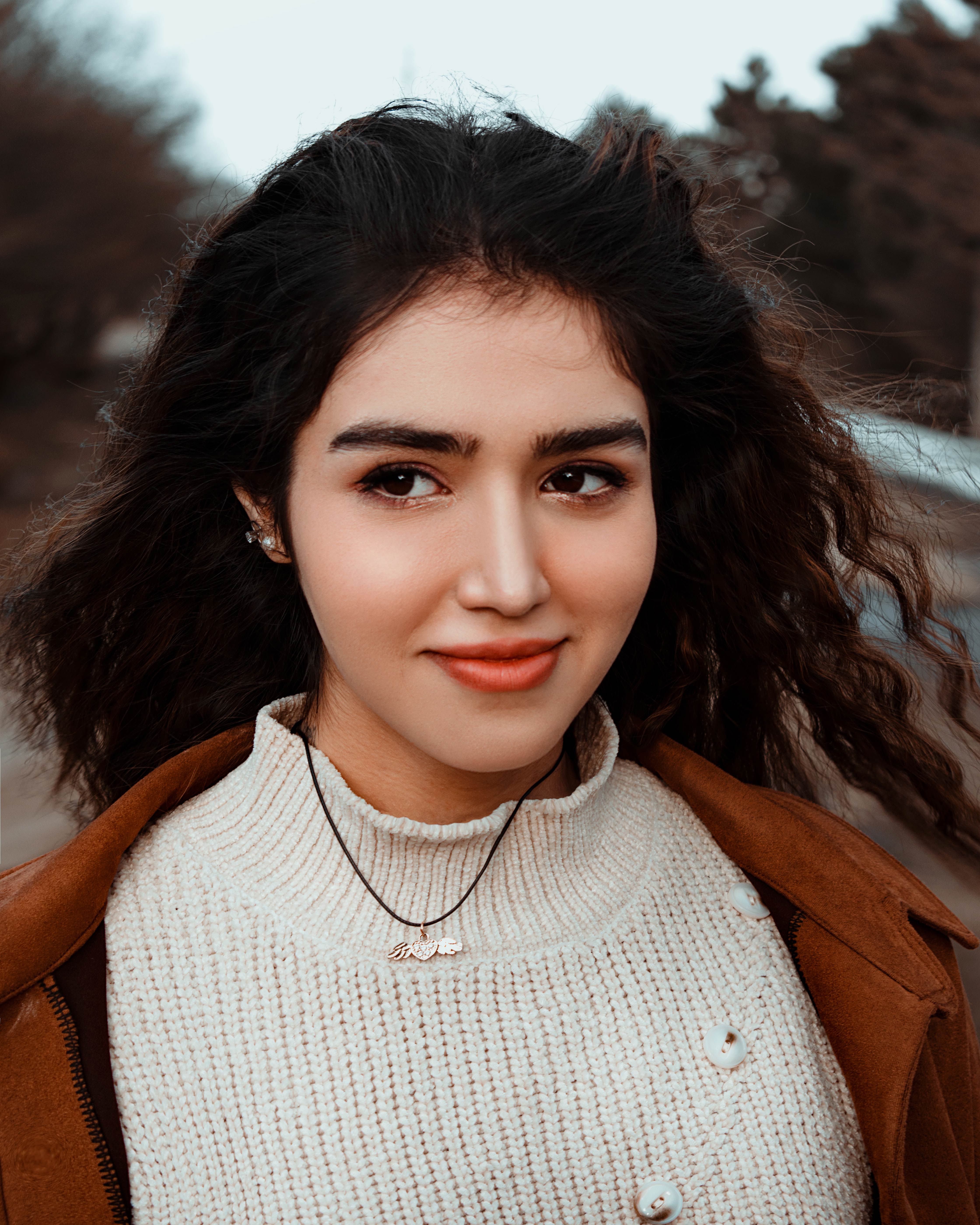 Charming portrait of a young woman with curly hair and a sweater, exuding warmth and style.
