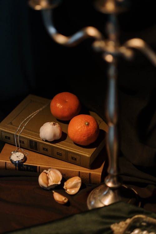 Bulb of Garlic and Tangerines on Top of Books