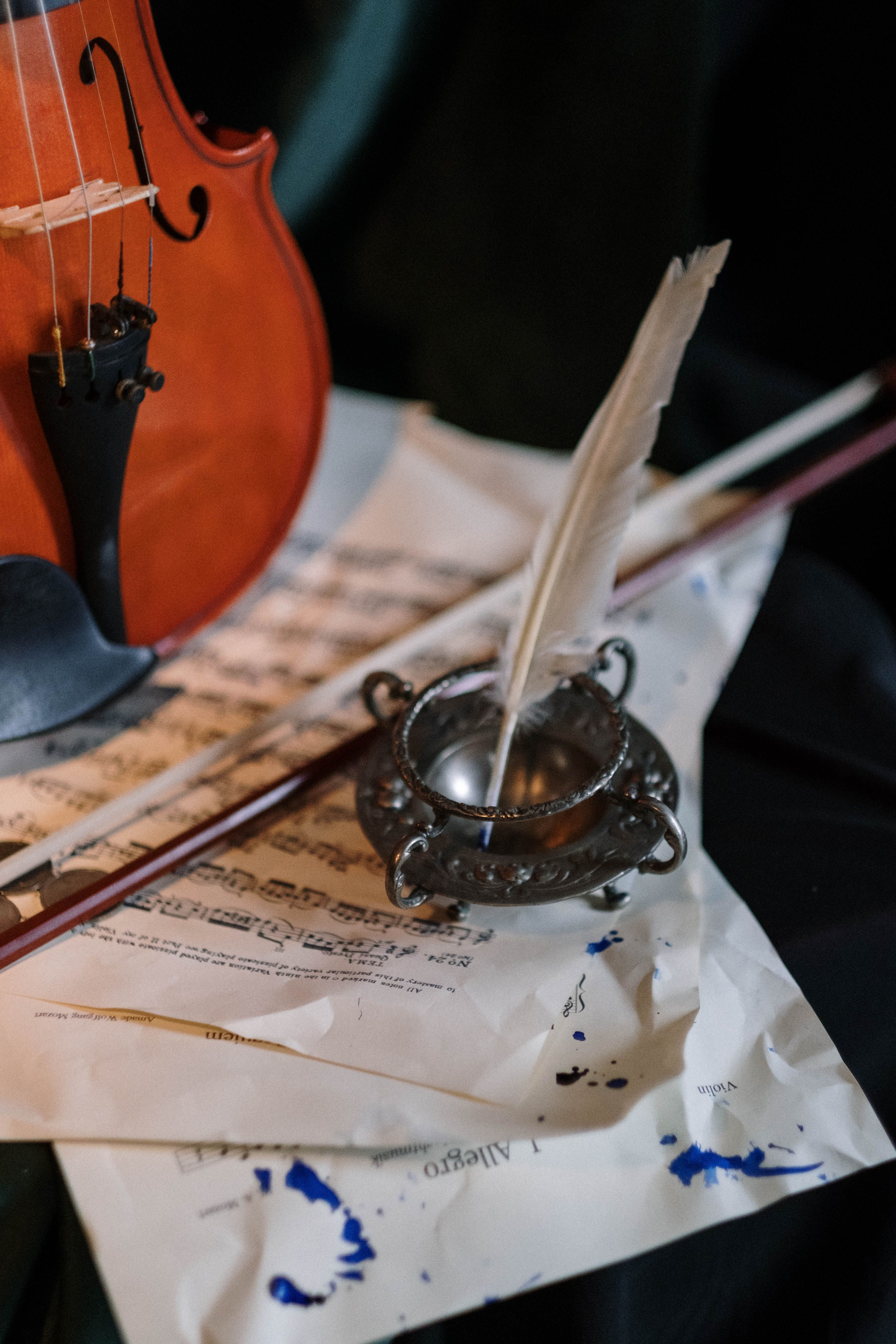 Elegant composition featuring a violin, quill in inkwell, and scattered sheet music.